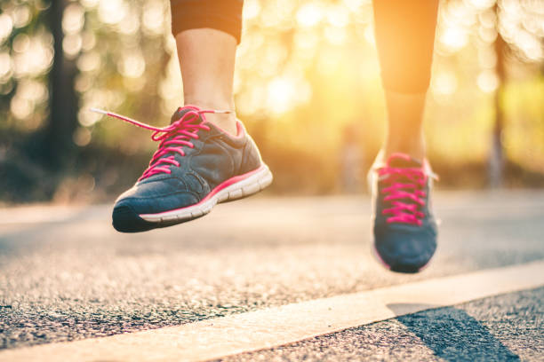 istock Women runner feet on road in workout wellness concept. 932070774