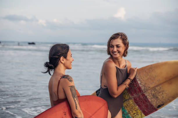 istock Pretty young surfers at the beach 932073596