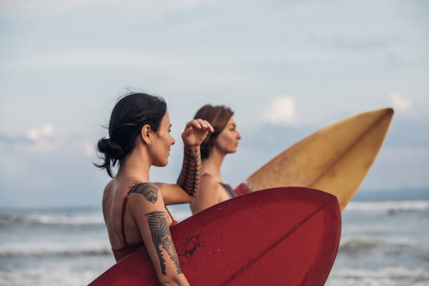 istock Pretty ladies surfers at the beach 932073666