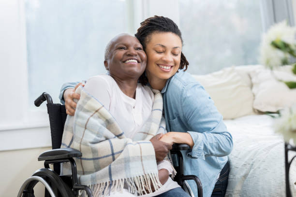woman embraces her wheelchair-bound mother - patient doctor hospital senior adult imagens e fotografias de stock