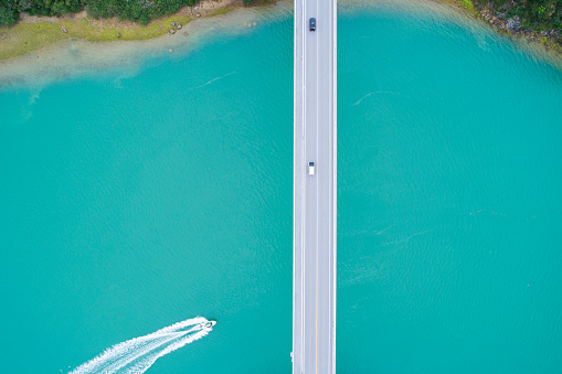 A bridge passes over a beautiful ocean, the ship is floating.