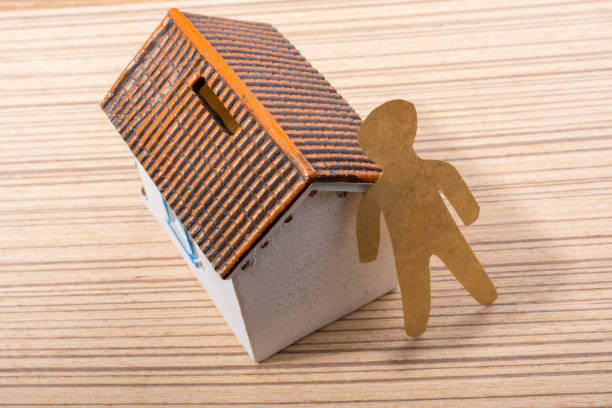 istock Little man figurine and model house on parquet background 932089558