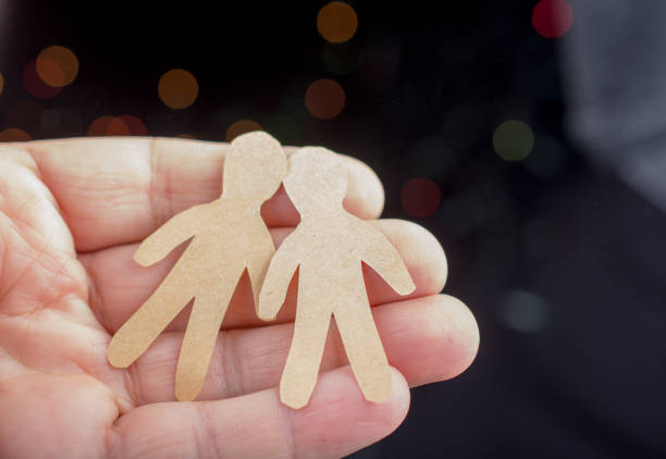 istock Paper man shape in hand on bokeh light background 932089624