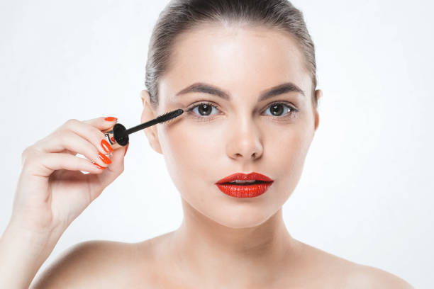 istock Mascara makeup woman face with red lips and manicure nails isolated on white. 932094216