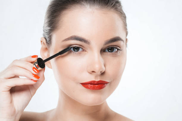 istock Mascara makeup woman face with red lips and manicure nails isolated on white. 932096410