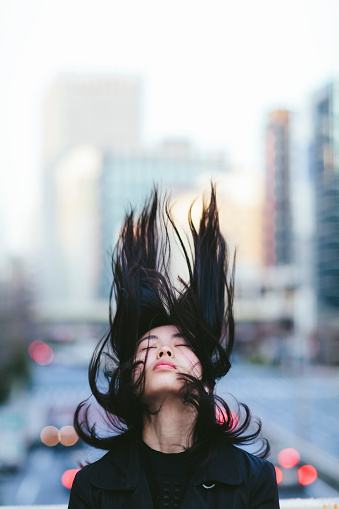 A portrait of a young Japanese woman while her is moving in the air.
