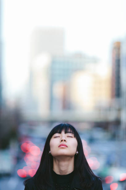 portrait de jeune femme whileher yeux sont fermés dans la ville - japan tokyo prefecture city women photos et images de collection