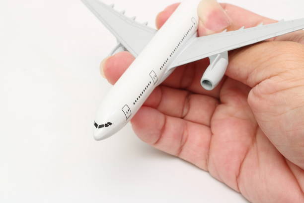 istock Human's hand holding miniature passenger airplane on white isolated background. 932097744