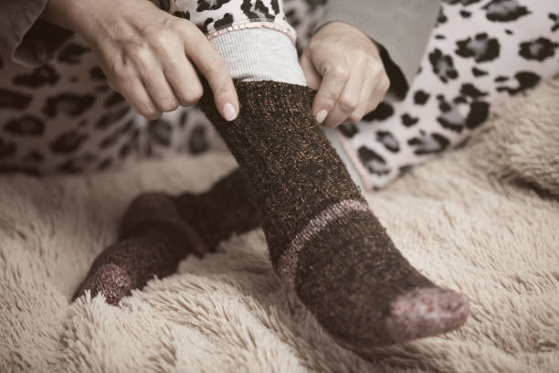 istock Woman hands putting on warm woolen socks 932108578