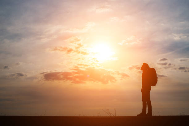 istock Silhouette of the young backpacker man walking  during sunset. 932109088