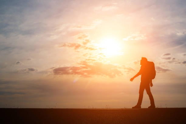 istock Silhouette of the young backpacker man walking  during sunset. 932111248
