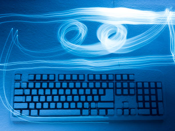 PC keyboard covered with snow illuminated by blue light with traces from drawing by freezelight