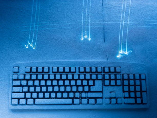 istock computer keyboard covered with snow illuminated with blue light with traces of bright lights on foreground 932111354