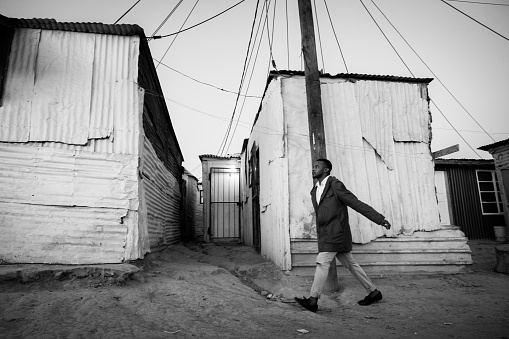 A confident young black businessman walks through the streets of the township on his way to work, Kayamandi Cape Town