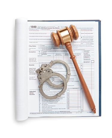 Tax return on white background with gavel and handcuffs