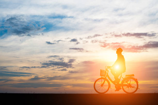 istock Young man ride bicycle on sunset background. 932117378