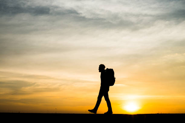 istock Silhouette of the young backpacker man walking  during sunset. 932117874