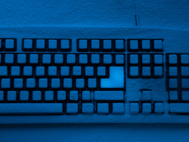 istock PC computer keyboard covered with snow illuminated with blue neon light and brightly lit enter key 932118022