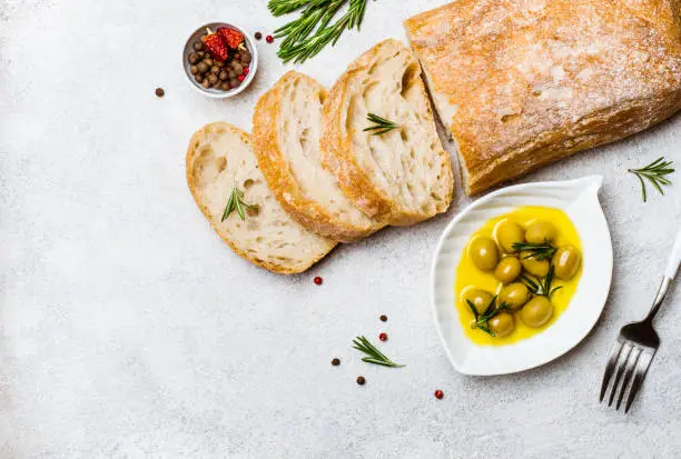 Italian ciabatta bread cut in slices with herbs and olives