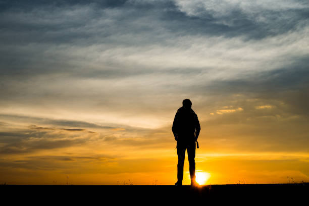 istock Silhouette of the young backpacker man walking  during sunset. 932121680