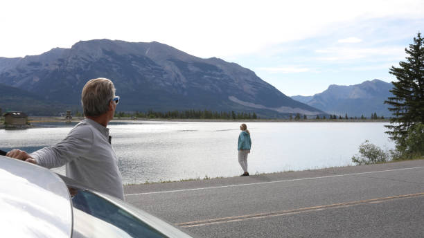 istock Couple leave car, look out over lake 932125694