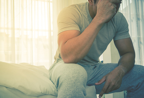 Man in Pyjamas is headache on bed from hang over and stress in morning