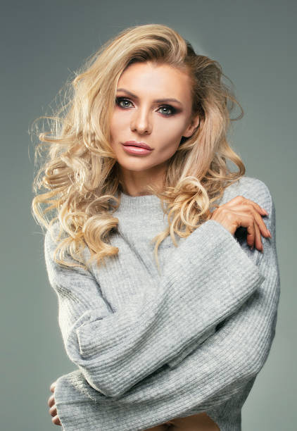 Sensual woman in fashionable sweater. Sensual female model posing in fashionable sweater. Blonde beautiful woman with glamour makeup and long curly hair. 11313 stock pictures, royalty-free photos & images
