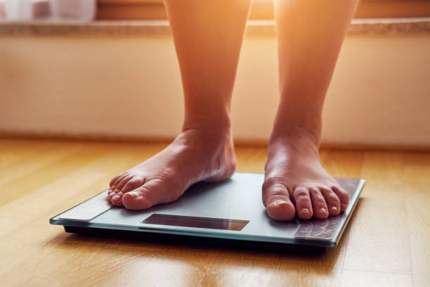 istock Female bare feet on weight scale 932134140