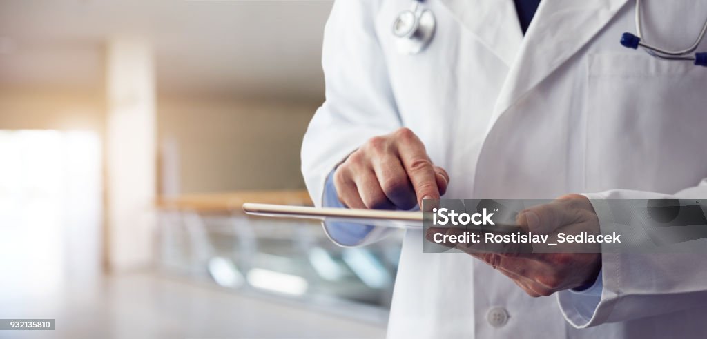 Male doctor presses on screen digital tablet Male doctor presses on screen digital tablet in the hospital Doctor Stock Photo