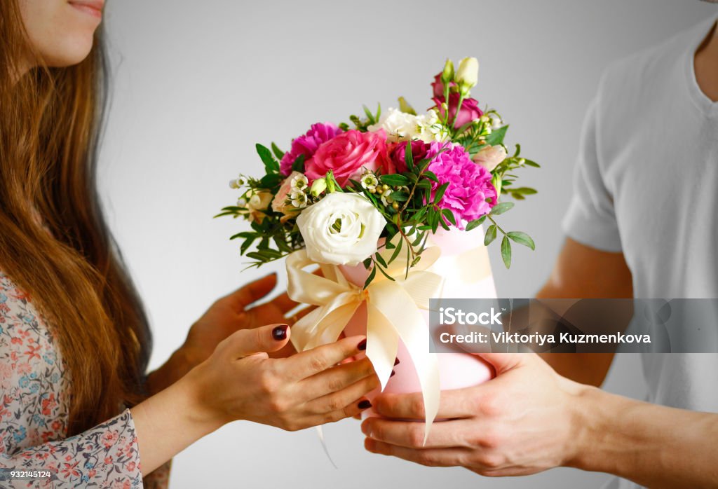 ผู้ชายให้ช่อดอกไม้กับเด็กผู้หญิง องค์ประกอบของดอกไม้ในกล่องหมวกสีชมพู  ผูกด้วยริบบิ้นสี ภาพสต็อก - ดาวน์โหลดรูปภาพตอนนี้ - Istock