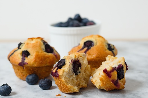 Several homemade blueberry muffins on marble surface