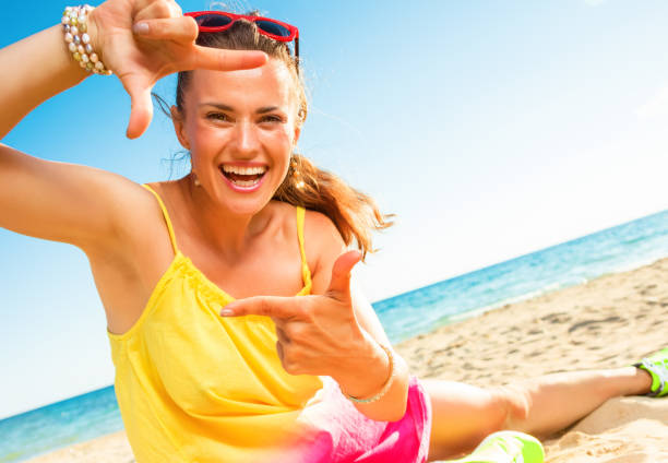 istock happy modern woman on beach framing with hands 932150566