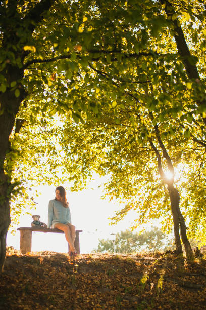 istock the girl sitting on a bench with a teddy bear 932154624