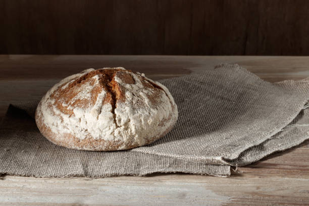 istock Round wheat rye bread on sackcloth on a wooden background 932158208