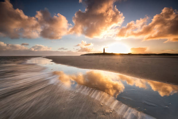 dramatic sunrise over North sea coast with lighthouse, Texel stock photo