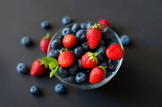 istock Fresh berries. Various summer berries in a bowl on rustic wooden table. 932161544