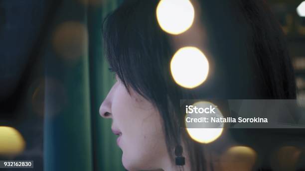 Beautiful Brunette Is Looking Out The Window With Green Background Closeup Profile Portrait Twinkle Lights Stock Photo - Download Image Now