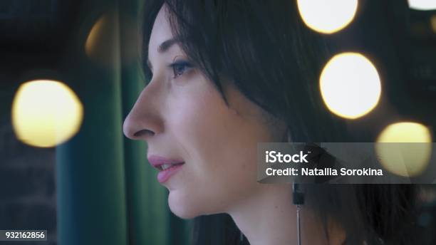 Beautiful Brunette Is Looking Out The Window With Green Background Closeup Profile Portrait Twinkle Lights Stock Photo - Download Image Now