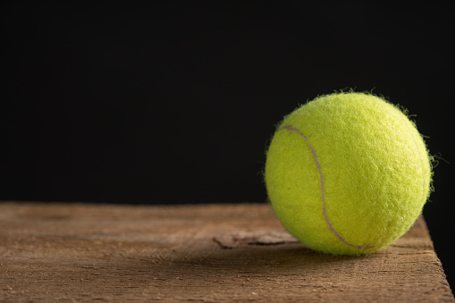 Tennis ball against black on the wood table