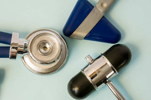 Stethoscope and two rubber heads of neurological reflex hammers close-up on a white background in the office of doctor of general medicine. Diagnostic medical tool