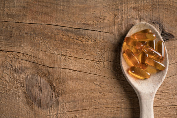 cápsulas de omega 3 en la cuchara de madera - cod liver oil capsule vitamin pill vitamin e fotografías e imágenes de stock
