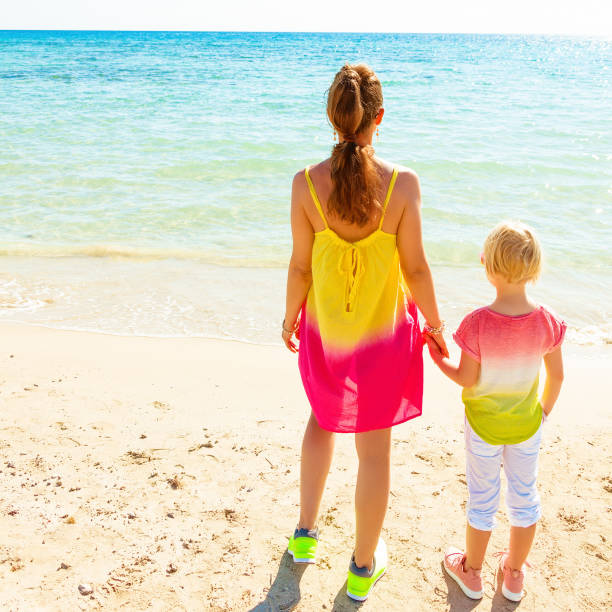 istock modern mother and daughter on seacoast looking into distance 932185646