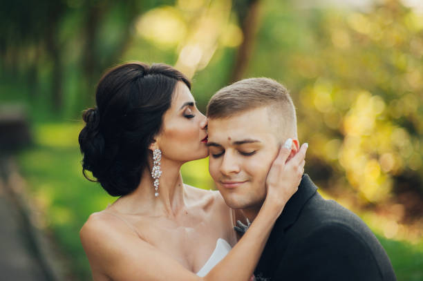istock Confident elegant groom and beautiful shy bride holding hands outdoors closeup 932185770
