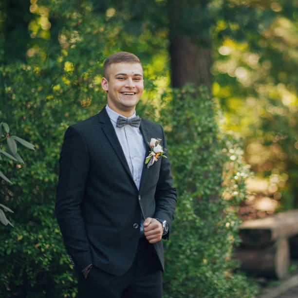 istock Handsome brunette groom stands on green lawn 932185780