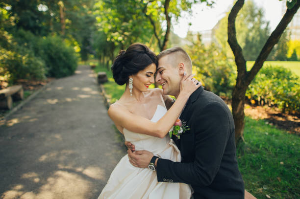 istock Confident elegant groom and beautiful shy bride holding hands outdoors closeup 932185824