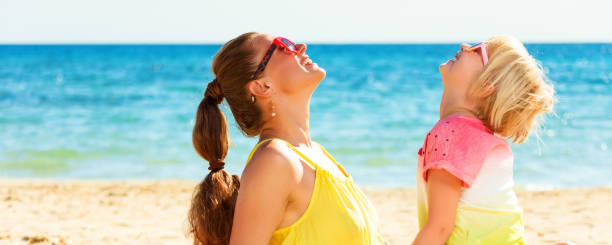 istock smiling mother and daughter on beach looking at copy space 932186092