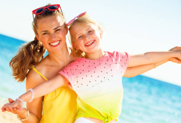 istock smiling trendy mother and daughter on seashore having fun time 932187664