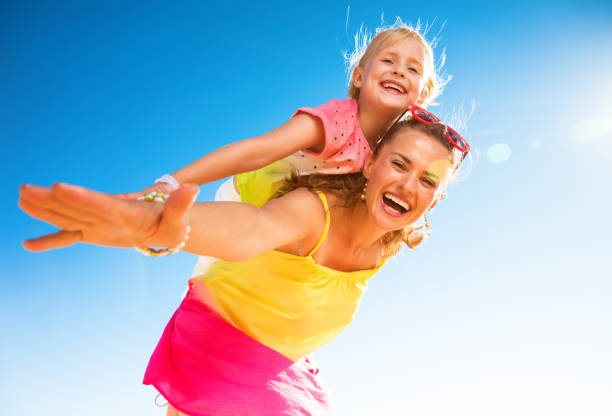 smiling modern mother and daughter on seashore having fun time