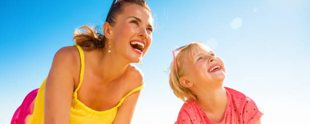 istock smiling mother and daughter on seacoast looking at copy space 932195388