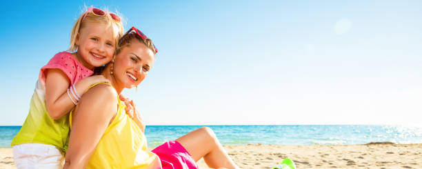 istock smiling trendy mother and daughter on seashore 932201170